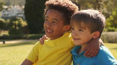 Slow motion of two boys sitting on grass together in park. Vidéo 43673221