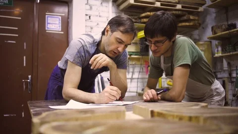 Slow Motion: Two carpenters discuss drawing (round wood) in the workshop Stock Footage 102566965