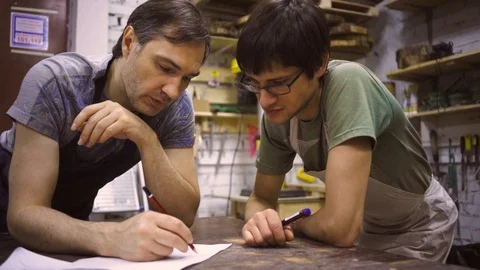Slow Motion: Two carpenters discuss drawing (round wood) in the workshop Stock Footage 102567026