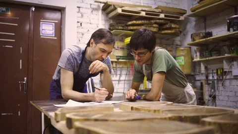 Slow Motion: Two carpenters discuss drawing (round wood) in the workshop Stock Footage 102567028
