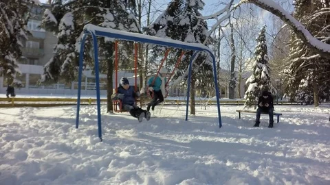 Slow motion. Two children ride on a swing. The boy is sitting on the bench. Video stock 88243062