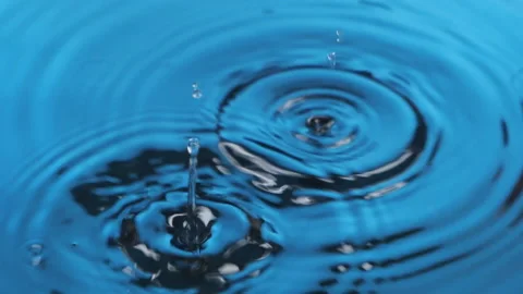 Slow motion. Two drops falling into blue water. Rain drops falling on surface of Stock Footage 164192005