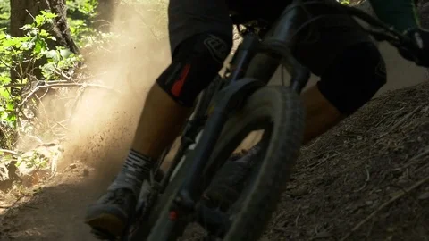 Slow motion two guys on mountain bikes taking a sharp turn and making dirt fly. Video stock 77584932