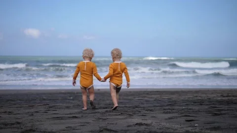 Slow-motion of two happy small blonde kids going together along the seashore on Video stock 166691646