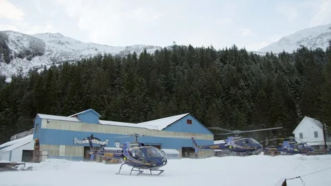 Slow motion of two helicopters taking off from ski resort on cloudy day Stock Footage 129109576