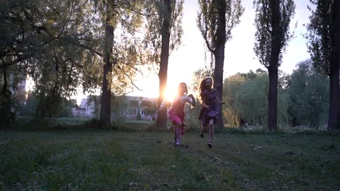 Slow Motion: Two laughing little sisters happily run in summer city park agai Stock Footage 112008887
