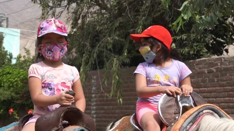 Slow motion of two little sisters riding horse wearing mask on family trip 库存影片 150924860