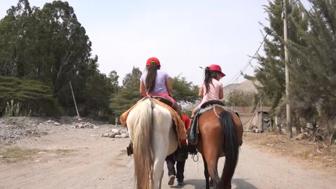 Slow motion of two little sisters riding horse seen from behind Stock Footage 150925807