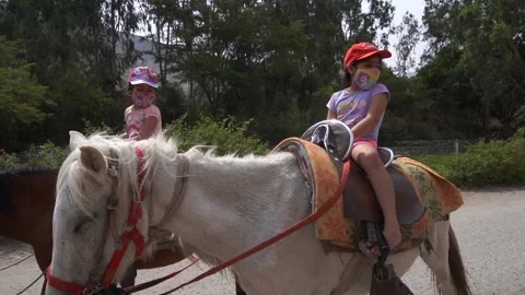 Slow motion of two little sisters riding horse seen from behind 動画素材 150925936