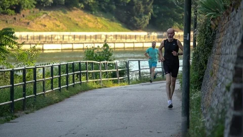 Slow motion of two men, jogging in the park, by the river Stock Footage 111726919