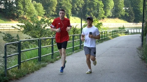 Slow motion of two men, jogging in the park, by the river Stock Footage 111732771
