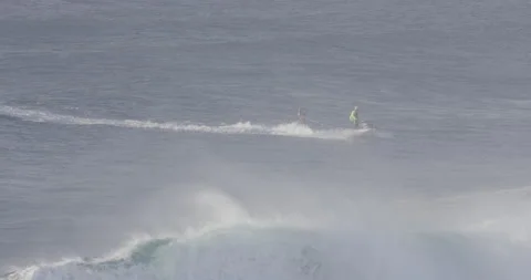 Slow motion of two pro surfers on jet ski and surfing board in middle of ocean Stock Footage 159863480