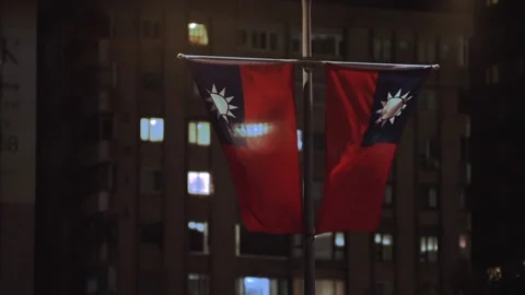 Slow motion of two Taiwan flags on pole against city lights Stock Footage 310853536
