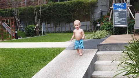Slow motion.  two-year-old blond boy running on a stone path  Stock Footage 104849115
