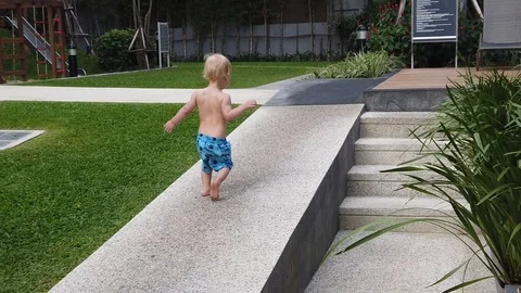 Slow motion.  two-year-old blond boy runs away on a stone path . Stock Footage 104849139