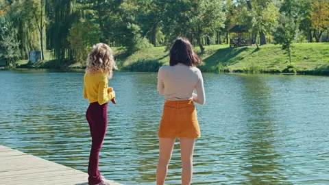 Slow motion, two young happy women in a summer park feed seagulls, they throw Stock Footage 167350100