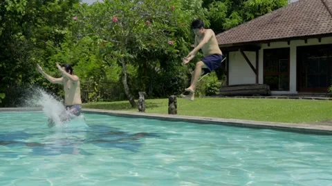 Slow Motion of Two Young Men Jumping into Swimming Pool in Summer Stock Footage 336475071