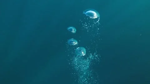 Slow-motion underwater moving through rising air bubbles in deep blue water Stock Footage 328366024