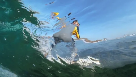 SLOW MOTION UNDERWATER: Pro surfer riding big barrel wave in crystal clear ocean Stock Footage