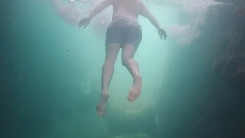 Slow motion underwater rear back shot of a man swimming away from camera Stock Footage 114149778