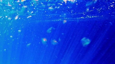 Slow-motion underwater scene of deep blue ocean with bubbles and sunbeams Stock Footage 279430956