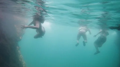 Slow motion underwater shot of group of people swimming together in sea Stock Footage 114148994