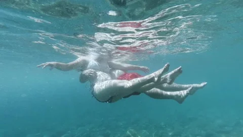 Slow motion underwater side view of young adult couple relaxing in ocean Stock Footage 138430453