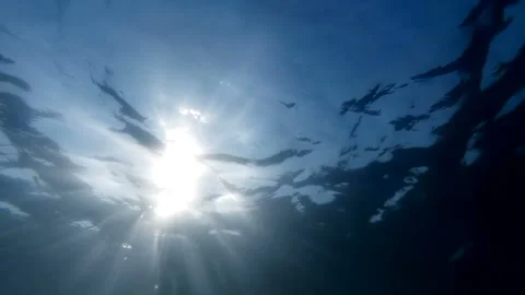 Slow motion underwater video of looking up at the bright sun light from sea Stock Footage 95093623