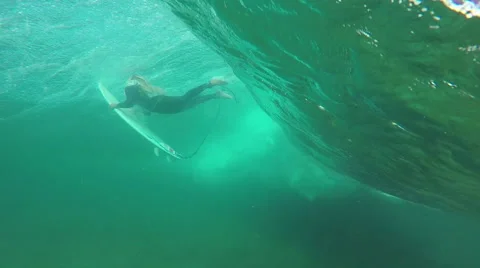 SLOW MOTION UNDERWATER: Young pro surfer girl doing duck dive Stock Footage
