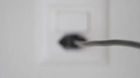 Slow-motion unplug a black cable with force from a power socket. Stock Footage 147848605