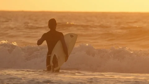 SLOW MOTION: Unrecognizable surfer going surfing big crashing waves at sunset. Stock Footage 86070083