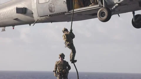 Slow motion U.S. Navy sailor fastroping from MH-60 Sea Hawk onto USS Boxer LHD 4 Stock Footage 293060734