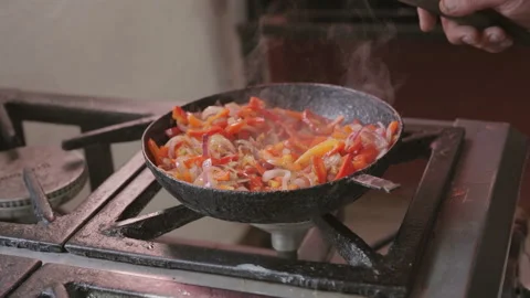 Slow motion vegetables sautéing in cast iron pan on gas stove 動画素材 336669407