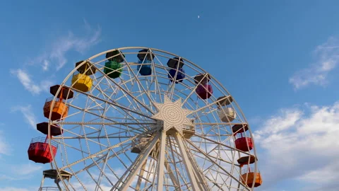 Slow motion vertical pan shot of colorful ferris wheel against clear blue sky Stock-Footage 132197474