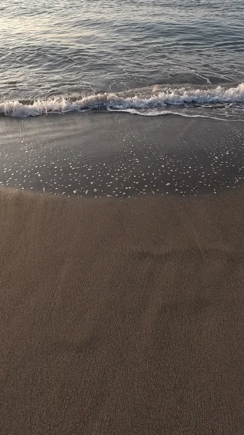 Slow motion vertical video of waves rolling onto a sandy beach Stock Footage 296488473