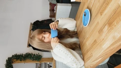 Slow motion. Vertical video. Young girl with long hair in a white sweater drink Stock Footage 123553297