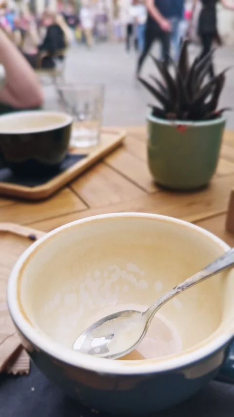 Slow-motion vertical view of an empty coffee cup with spoon on an outdoor café Stock Footage 341112806