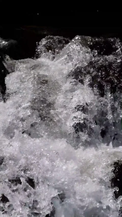Slow motion vertical view of a fast flowing waterfall in a rocky mountain Stock Footage 320983576