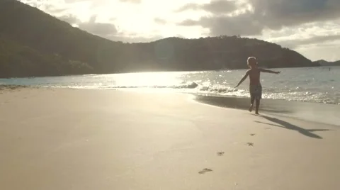 Slow motion video of a boy running down the beach waving his arms as if to fly  Stock Footage 67598802
