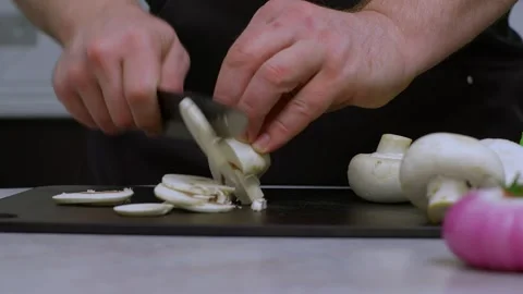 Slow motion video. A close-up shows a porcini mushroom being chopped by a chef Stockbeeldmateriaal 269120507