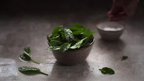 Slow Motion video of Coarse salt falling on Leaves of fresh baby spinach Stock Footage 162775024