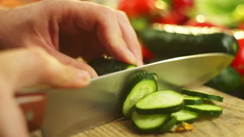 Slow-motion video of cutting a cucumber into rings with a knife in the kitchen. Stock Footage 296363429