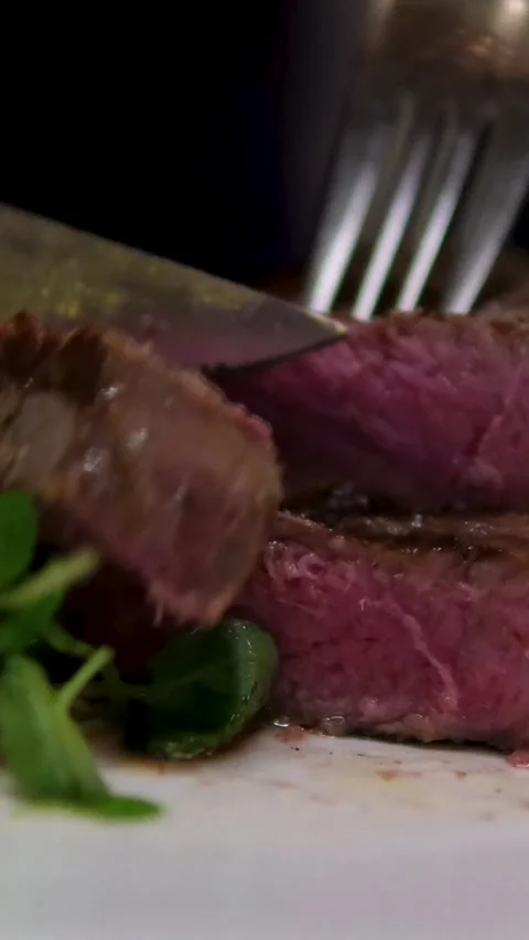 Slow motion video of cutting a piece of steak with a knife in a restaurant Stock Footage 302265961