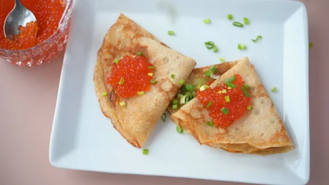 Slow motion video of dropping green onion onto Russian blinis with red caviar 스톡 동영상 124753400