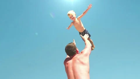 Slow motion video. Father throws son up when they play on the beach Stock Footage 249740065