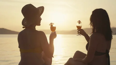 Slow motion video of a girl drinking a cocktail at sunset on the beach Vidéo 201561876