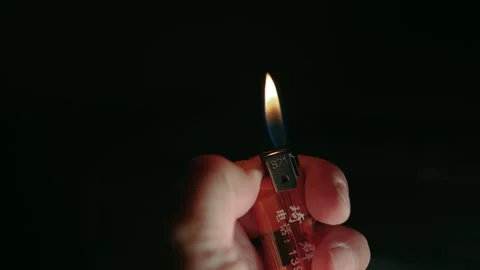 Slow motion video of a hand pressing and lighting a lighter in the dark Stock Footage 221458940