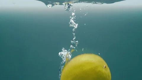Slow motion video. Lime falls into the water. Blue background Stock Footage 105011275