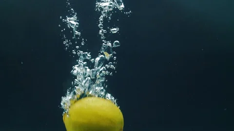 Slow motion video. Lime falls into the water. Blue background Stock Footage 105011290