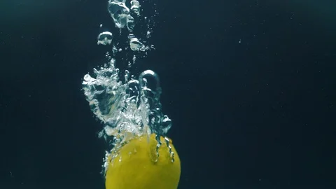 Slow motion video. Lime falls into the water. Blue background Stock Footage 105011345